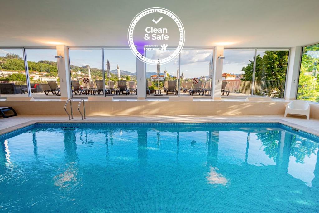 a swimming pool in a hotel with a sign that reads clean and safe at Luna Arcos Hotel Nature & Wellness in Arcos de Valdevez