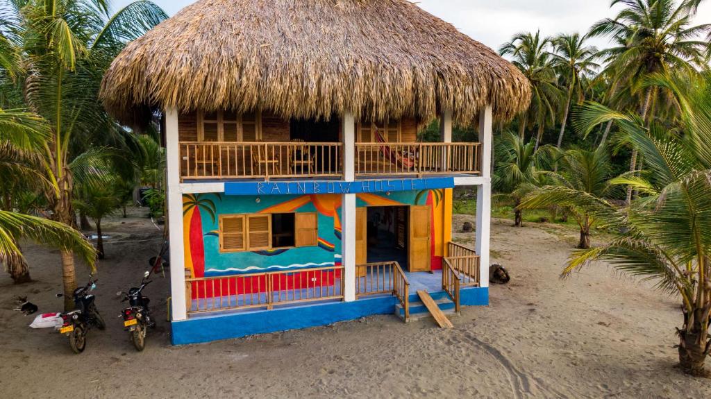Rainbow Hostel في سان برناردو ديل فينتو: منزل صغير مع سقف من القش على الشاطئ