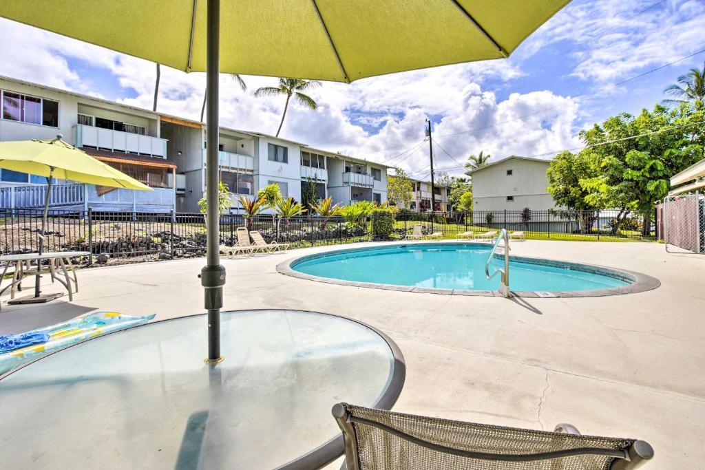 einen Tisch mit einem Sonnenschirm neben einem Pool in der Unterkunft Sunny Central Condo Lanai and Community Pool Access in Kailua-Kona