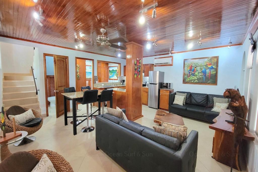 a living room with couches a table and a kitchen at LA BUENA VIDA CONDO in Tamarindo
