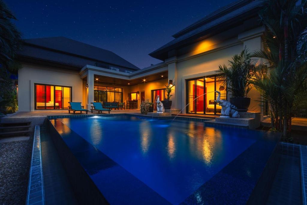 una piscina frente a una casa por la noche en VILLA RAAS | Private Pool | Baan Bua Estate by Tropiclook | Naiharn beach, en Nai Harn Beach