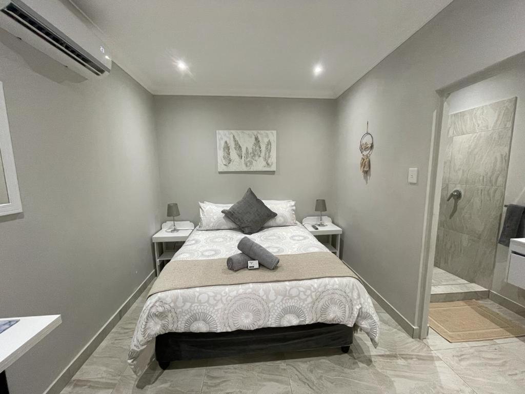 a bedroom with a bed with two tables and a shower at Guest house on Gillian Unit 4 in Ballito