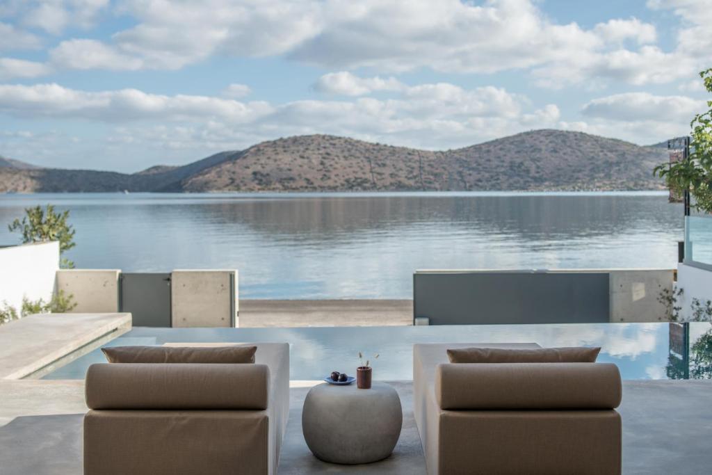 a view of a lake with two chairs and a table at Villa Mimaze Minimalist Living in Elounda