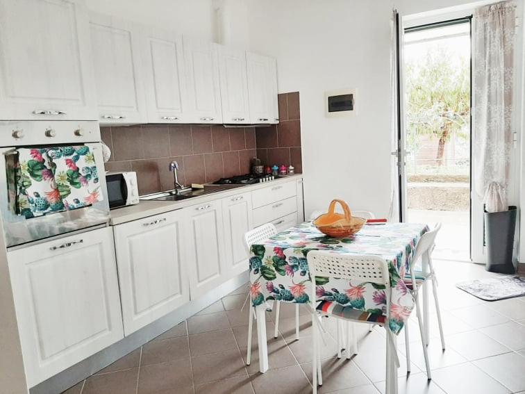 una cocina con armarios blancos y una mesa con mantel. en Green House en Cogoleto