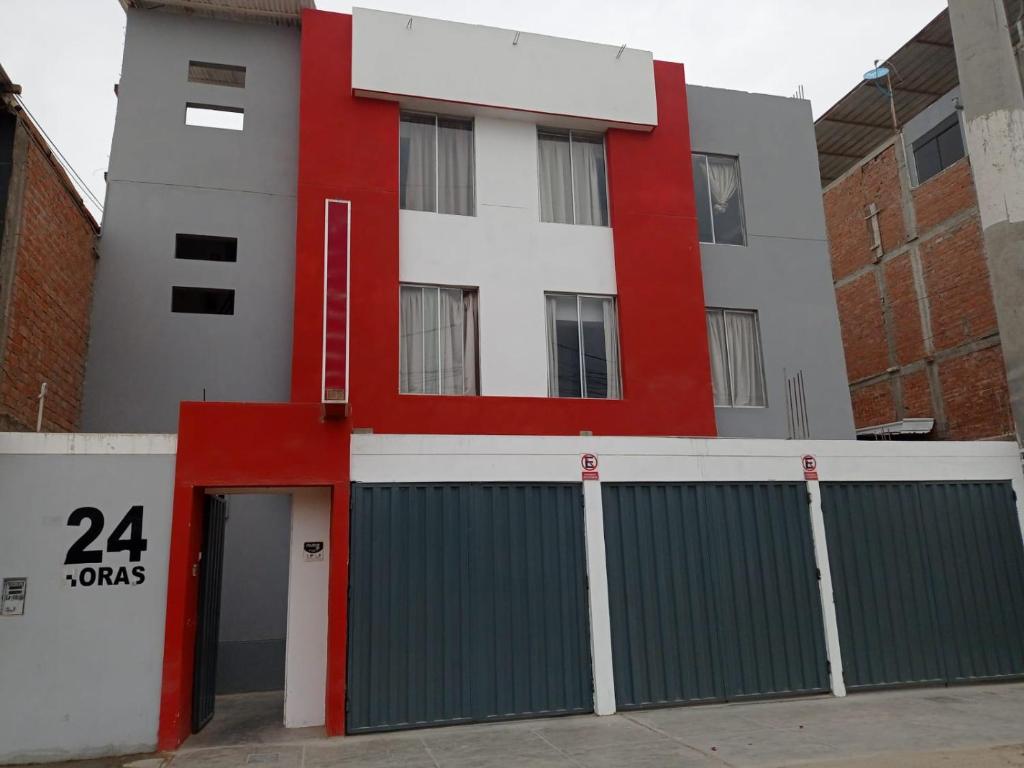 a red and white building with a garage at HOSTAL PARIS in Piura