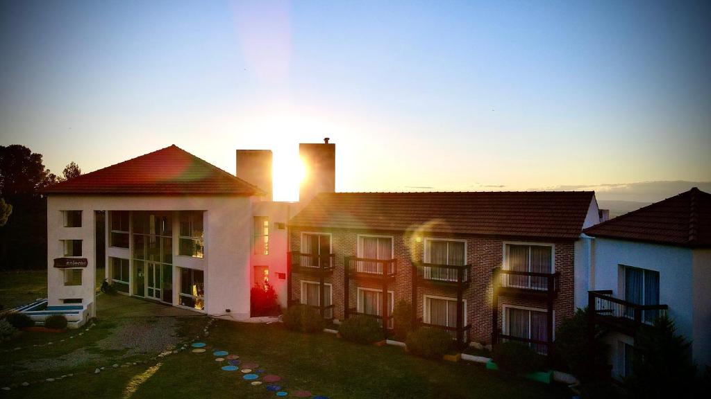 una casa con la puesta de sol detrás de ella en Hotel Colores en Merlo