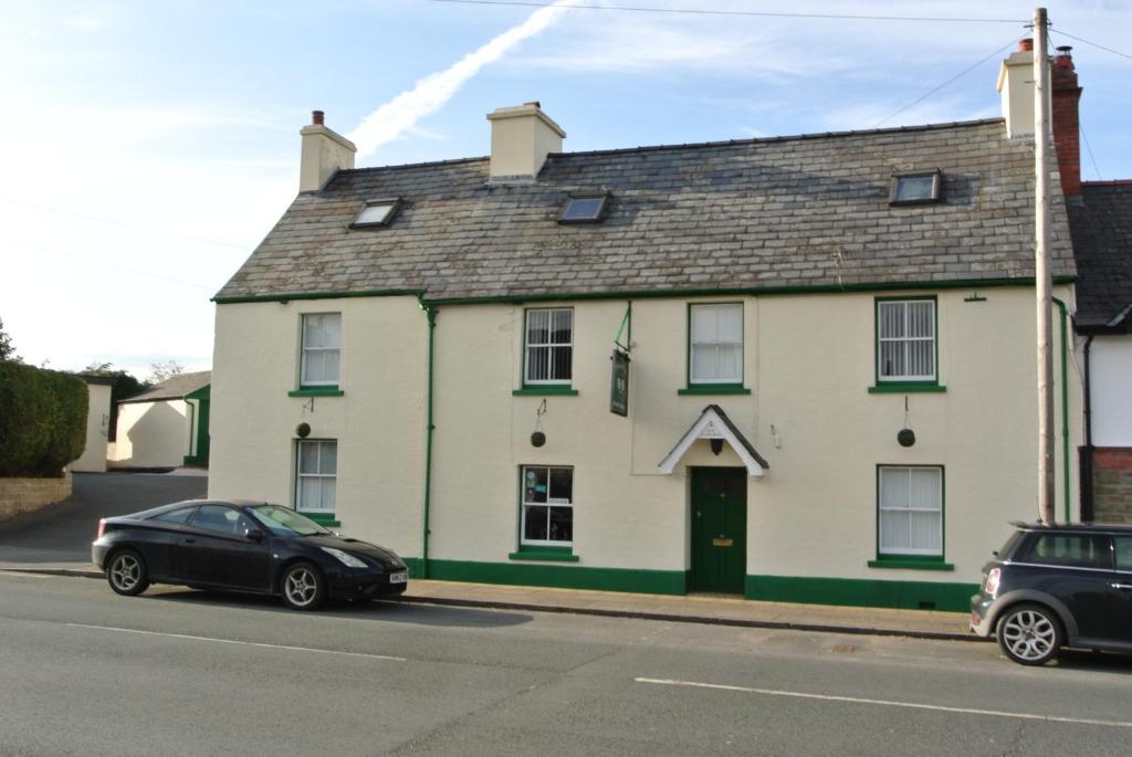 uma casa branca com um carro preto estacionado em frente em Old Castle Farm Guest House em Brecon