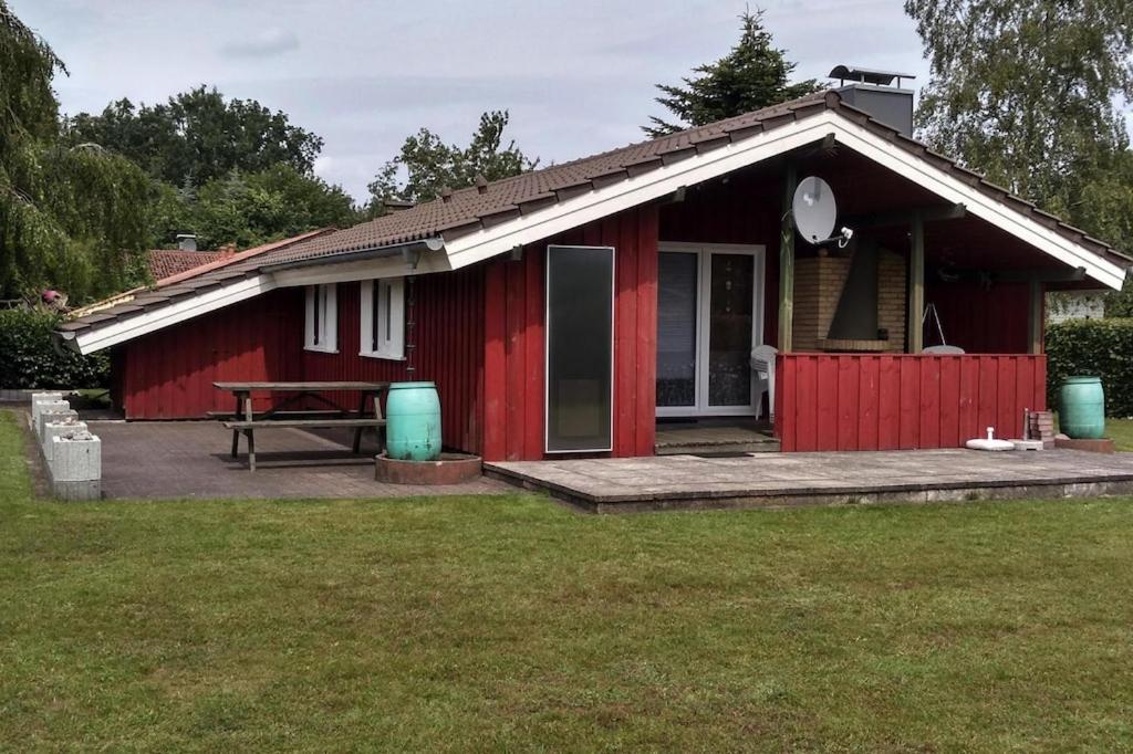 ein rotes Haus mit einem Picknicktisch davor in der Unterkunft Holiday home Hunning in Hünning