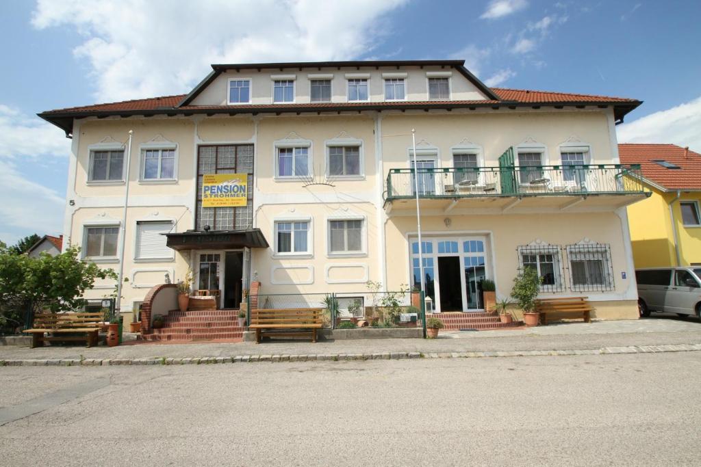a large white building with benches in front of it at Pension Strohmer in Rust