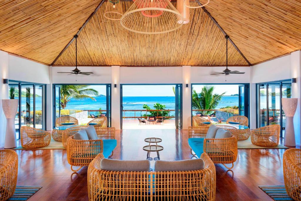 una sala da pranzo con sedie in vimini e l'oceano di Sheraton Resort & Spa, Tokoriki Island, Fiji a Tokoriki