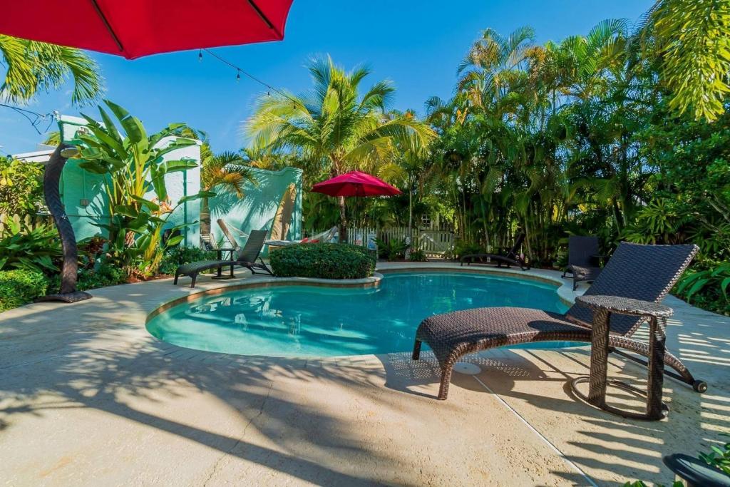 ウェストパームビーチにあるBahama Breeze Bungalow Vacation Rentalのプール(椅子2脚、赤い傘付)