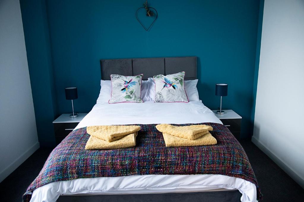 a bedroom with a bed with blue walls and two lamps at Cosy Stays in Redcar