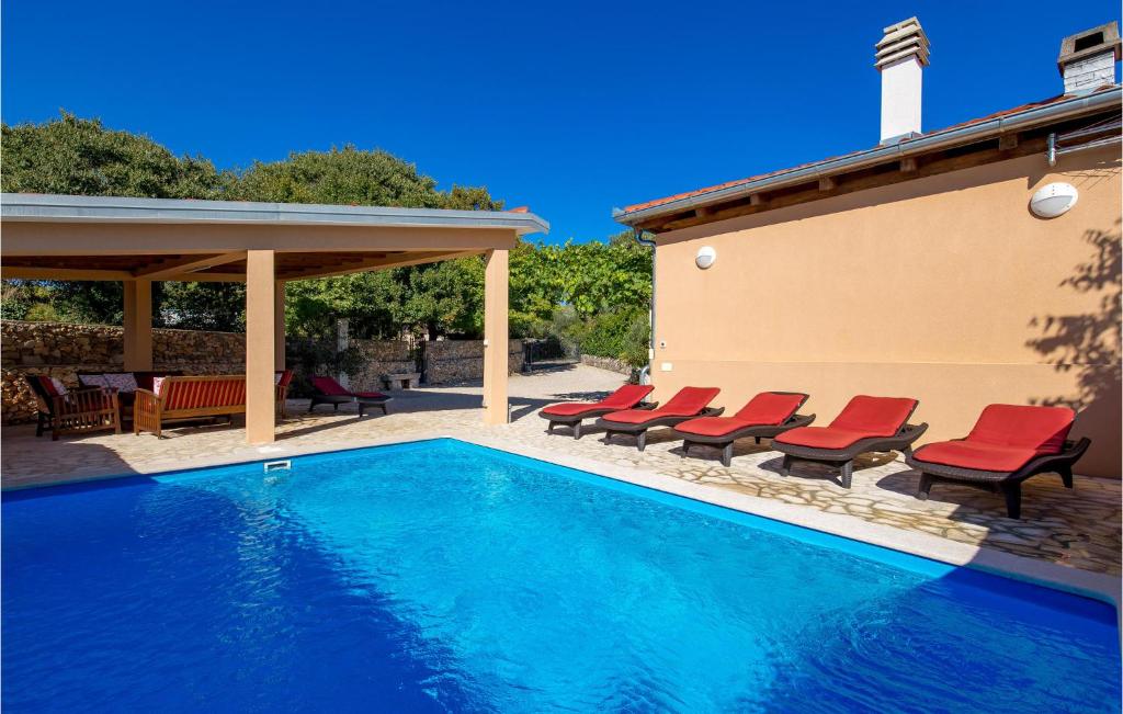 a swimming pool with red chairs next to a house at Cozy Home In Garica With Wifi in Garica