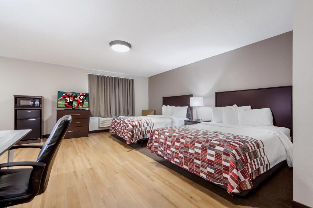 a hotel room with two beds and a table and chairs at Red Roof Inn & Suites Omaha - Council Bluffs in Council Bluffs