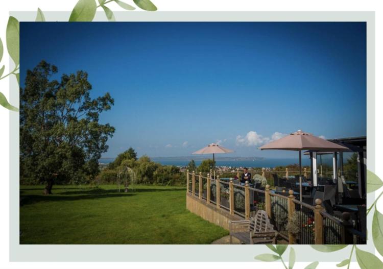 een patio met tafels en parasols en de oceaan bij The Crescent Turner Hotel in Whitstable