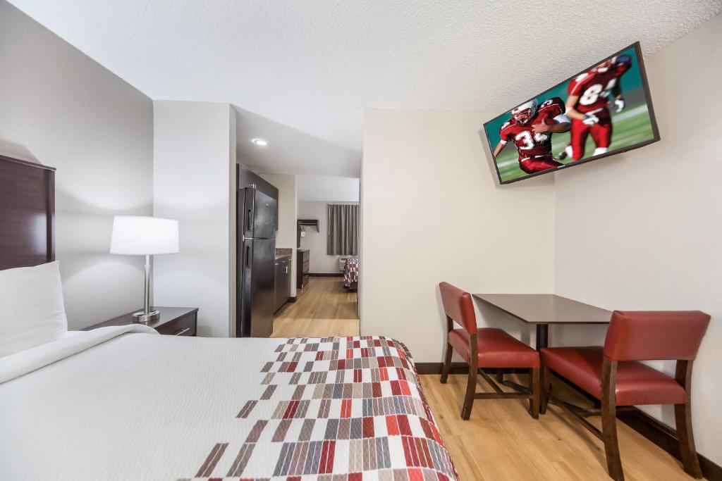 a hotel room with a bed and a table and chairs at Red Roof Inn & Suites Omaha - Council Bluffs in Council Bluffs