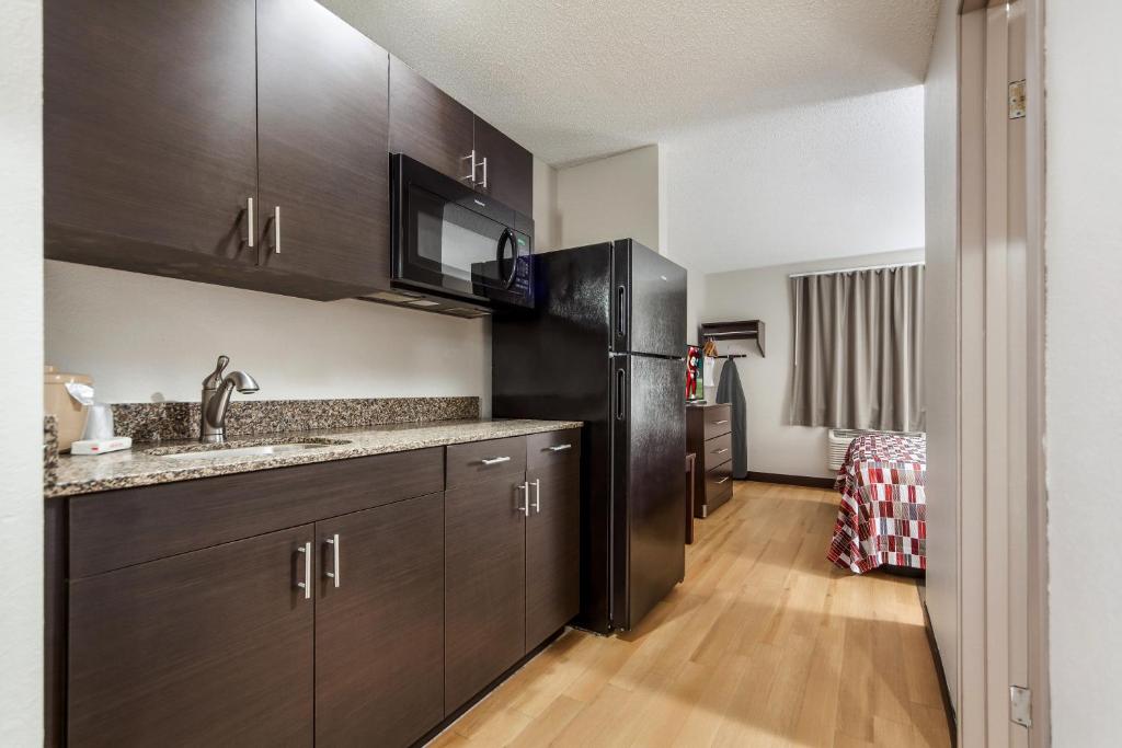 a kitchen with a black refrigerator and wooden floors at Red Roof Inn & Suites Omaha - Council Bluffs in Council Bluffs