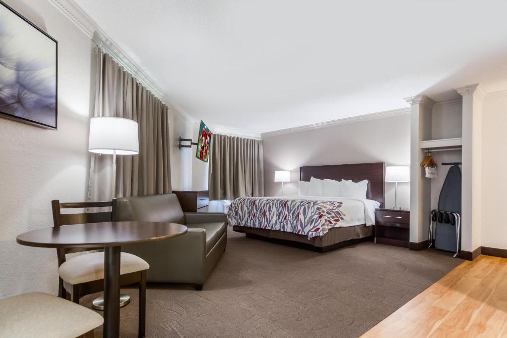 a hotel room with a bed and a table at Red Roof Inn & Suites Omaha - Council Bluffs in Council Bluffs