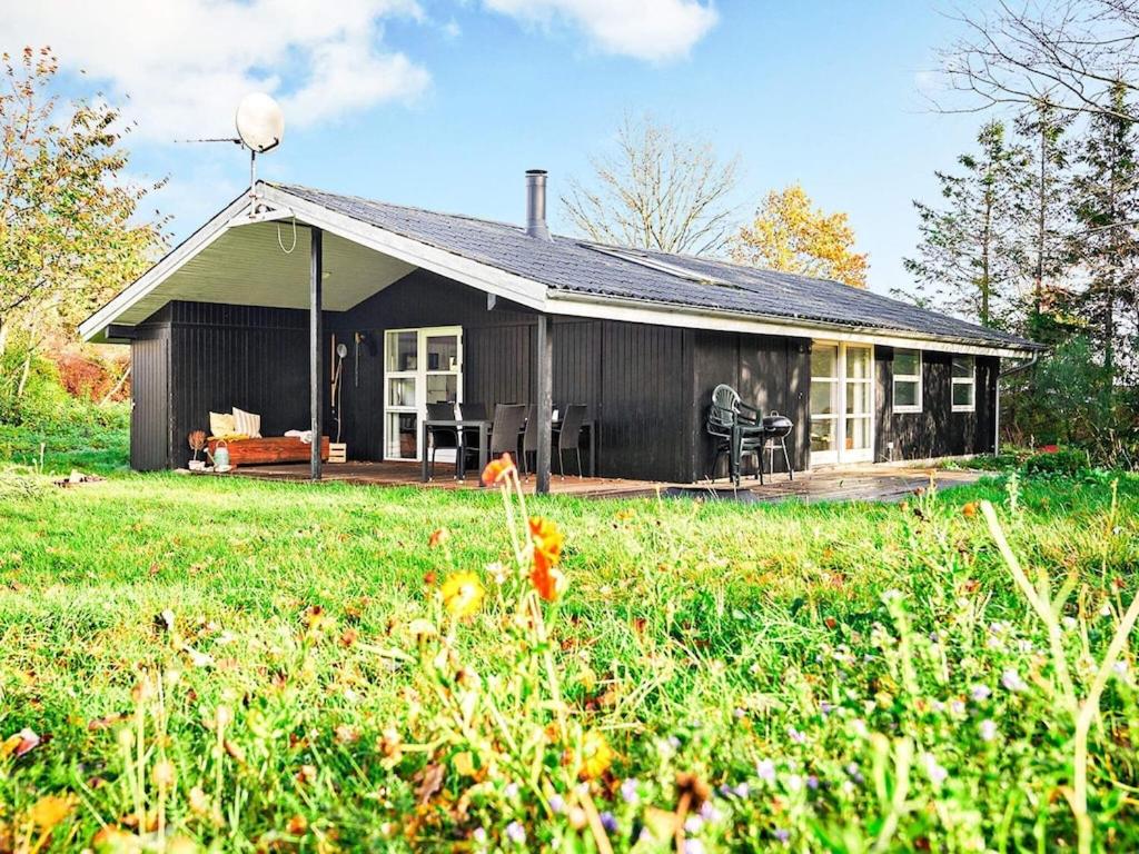 uma pequena casa preta com um campo de relva em frente em 6 person holiday home in Knebel em Skødshoved Strand