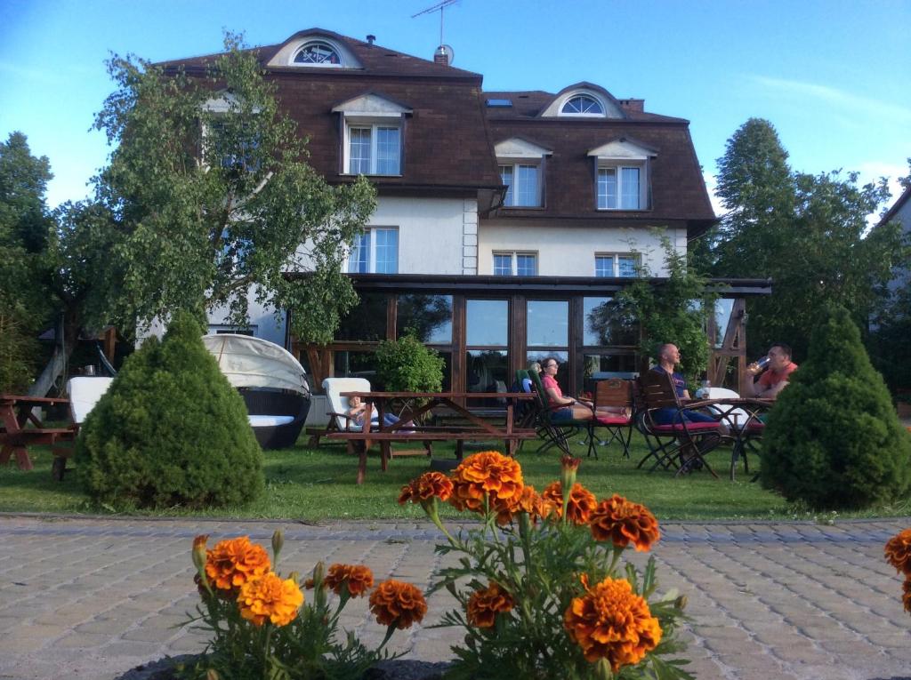 Una casa con gente sentada en bancos delante de ella. en Willa Adamów, en Mielno