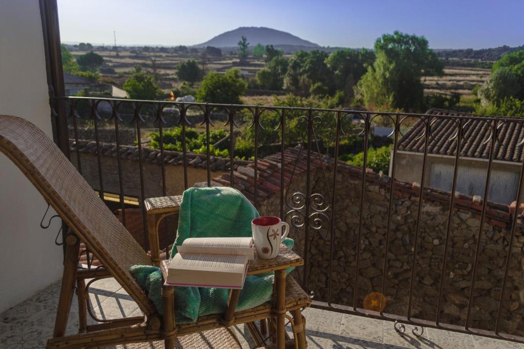a chair with a book and a cup of coffee on a balcony at Casa Rural Abuela Luci 