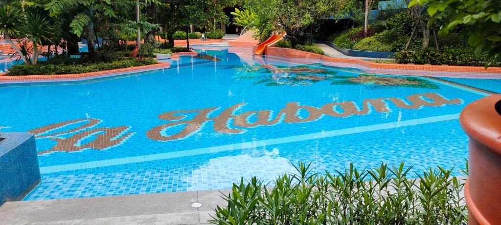 a large blue swimming pool with a sign that reads happiness at Lahabana Huahin by Moji in Hua Hin
