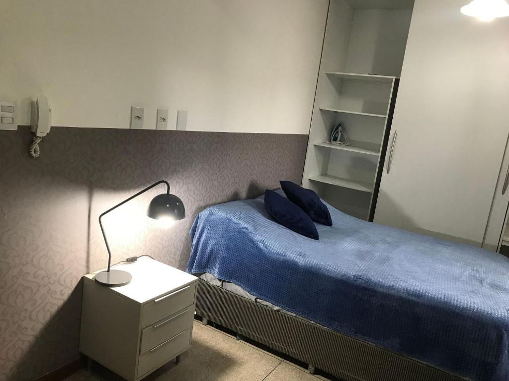 a bedroom with a bed with blue sheets and a lamp at STUDIO 302 | WIFI 600MB | RESIDENCIAL JC, um lugar para ficar. in Carmo