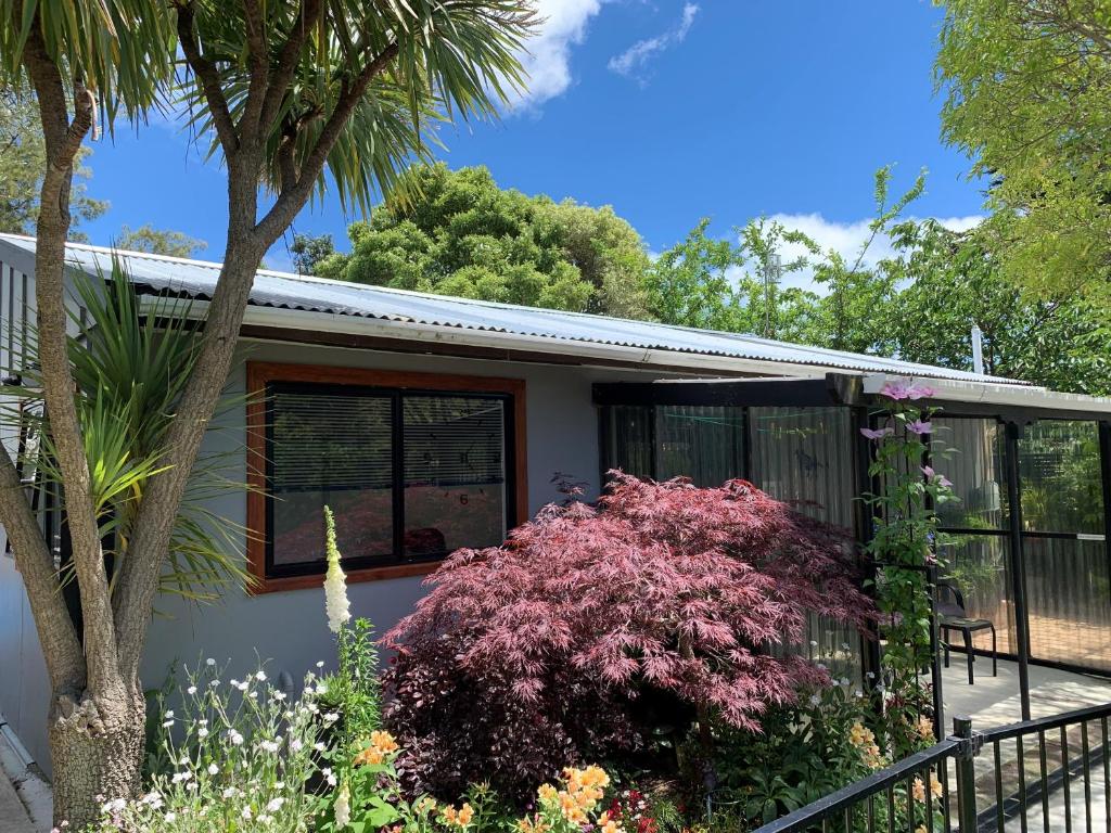 a house with a flowering bush in front of it at Twin Oaks Quiet Cottage in Paraparaumu