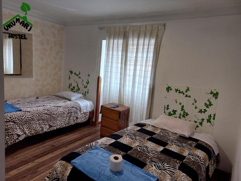 a bedroom with two beds and a window at Ukumari Hostel in Cusco