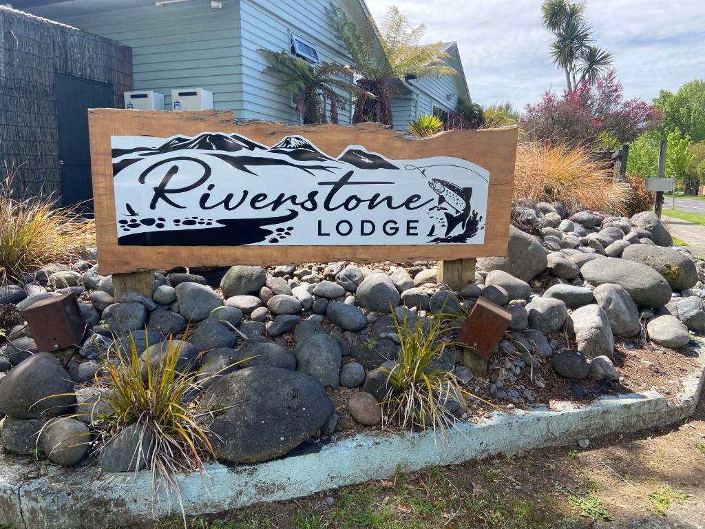 a sign for a lodge in a bed of rocks at Riverstone Lodge in Turangi