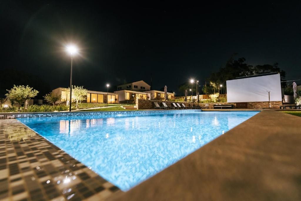 a large swimming pool at night with a screen at ALTO DA GARÇA - PRIME VILLAS & SPA in Nadadouro