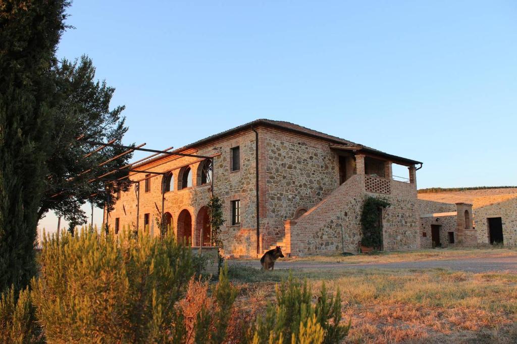 stary kamienny budynek z psem przed nim w obiekcie Cordella in Montalcino Wine Resort w mieście Montalcino