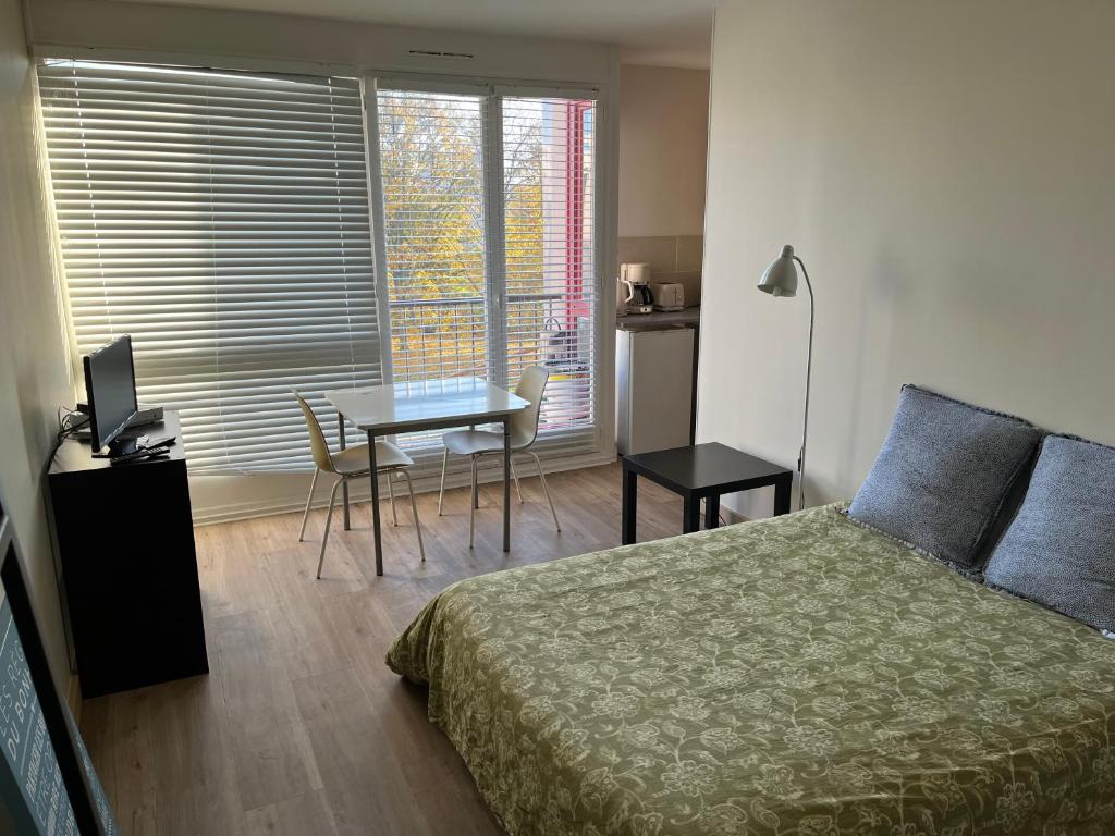 1 dormitorio con cama, escritorio y mesa con ordenador portátil en Cosylocation Jean Bart 59, en Rennes