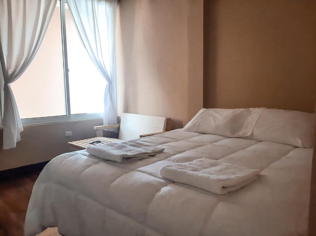 Cama blanca en habitación con ventana en Millennium Apartment, en San Pedro La Laguna