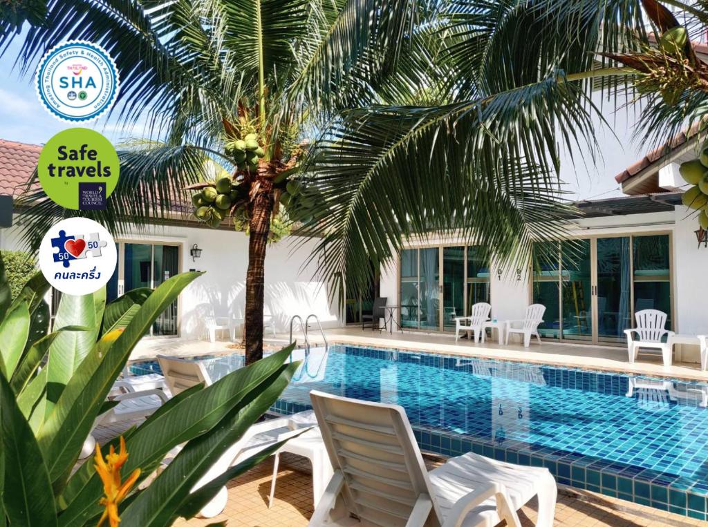 a swimming pool with chairs and a palm tree at The Snug Airportel - Phuket Airport in Nai Yang Beach