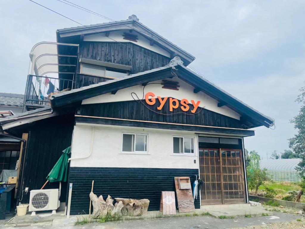 un edificio con un signo de ciprés en el costado. en GYPSY TAKASHIMA, en Katsuno