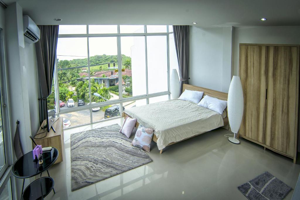 a bedroom with a bed and a large window at The CHU cafe / guesthouse in Nai Harn Beach