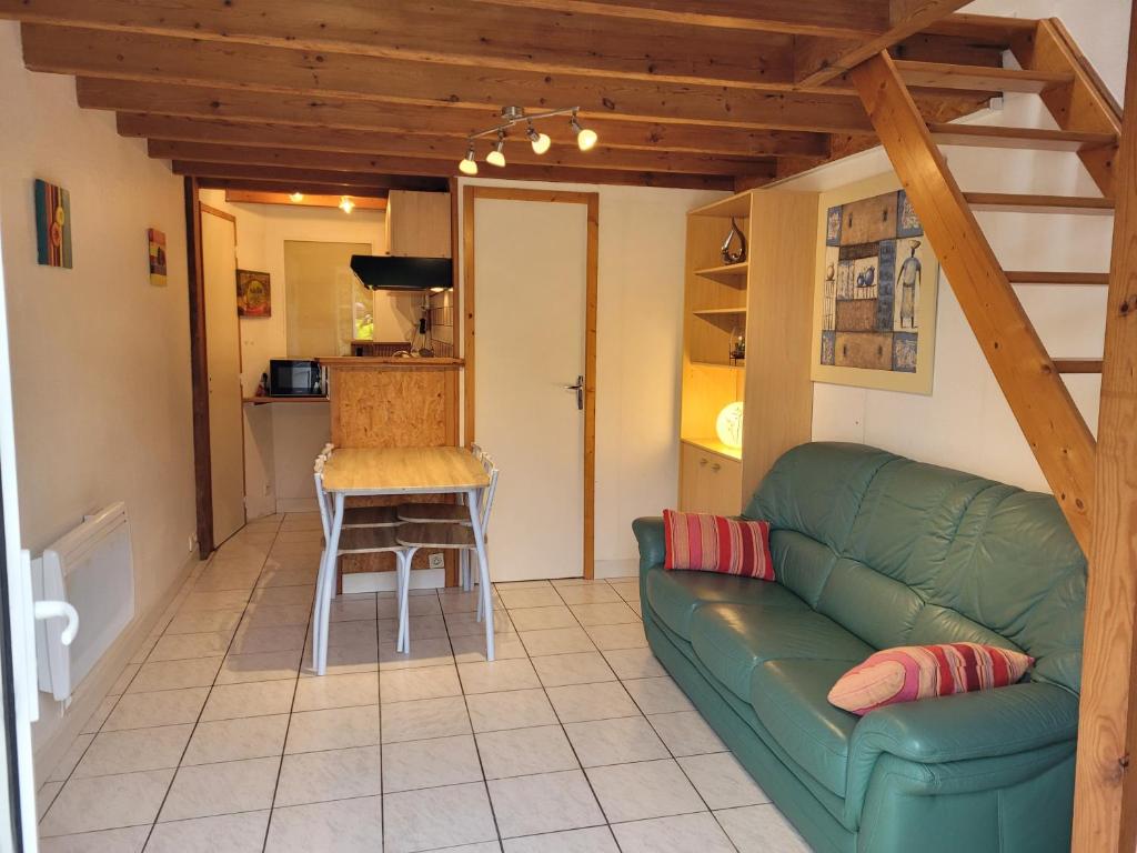 a living room with a green couch and a table at Gîte Mélisse in Mouilleron-le-Captif