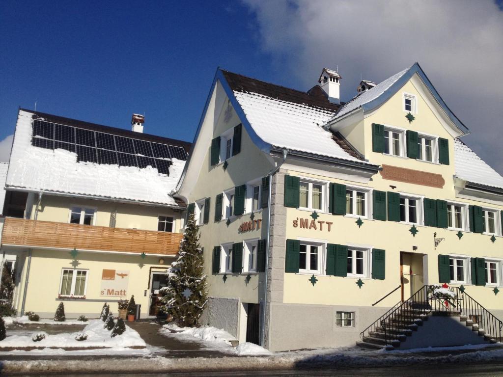 a large white building with green windows and snow at S'Matt in Röthis
