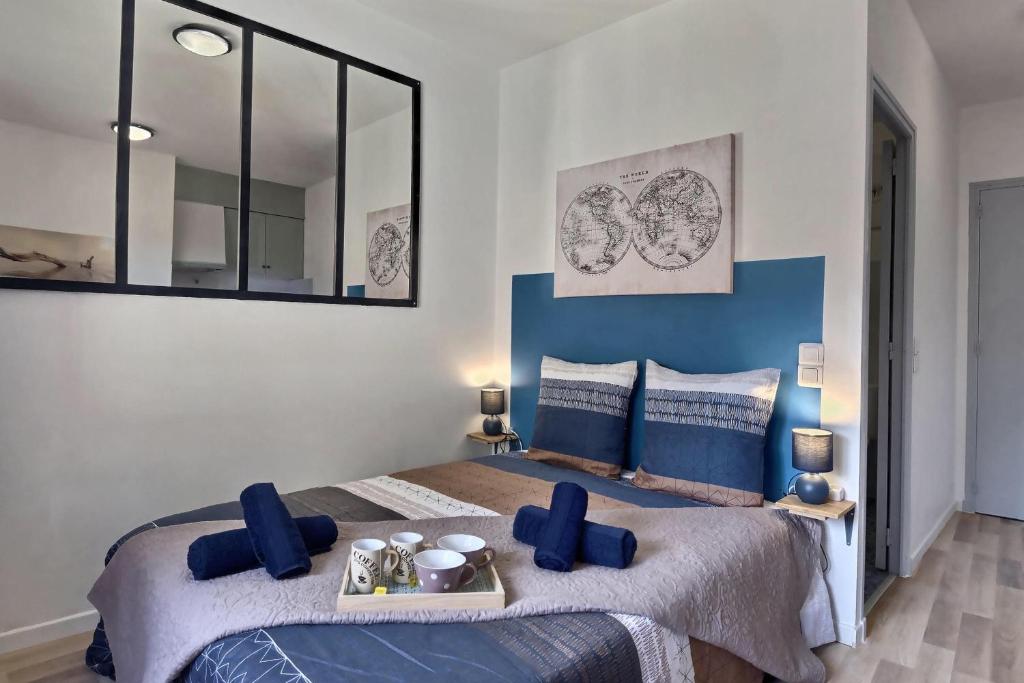 een slaapkamer met 2 bedden met blauwe kussens en een spiegel bij Studio vue sur le clocher, au calme Moustiers #3 in Moustiers-Sainte-Marie