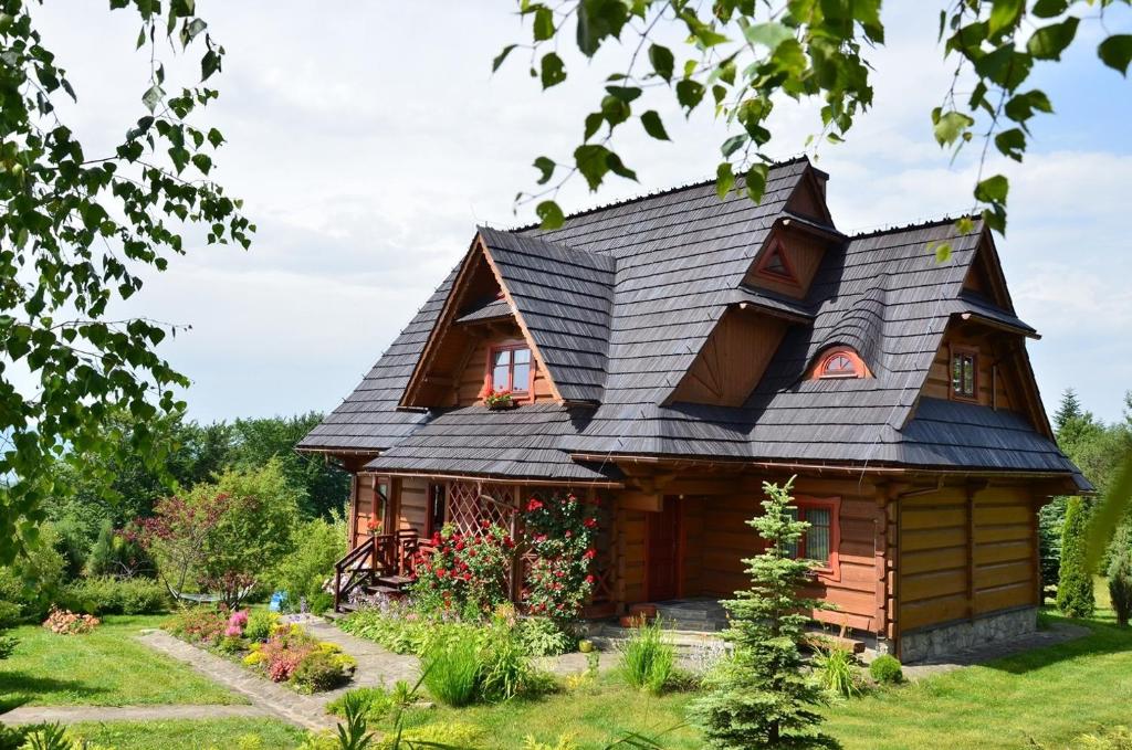 a log cabin with a black roof at Góralska Ostoja - tradycyjny, drewniany dom na Kudłaczach, duży ogród, piękna panorama, sauna, jacuzzi in Pcim
