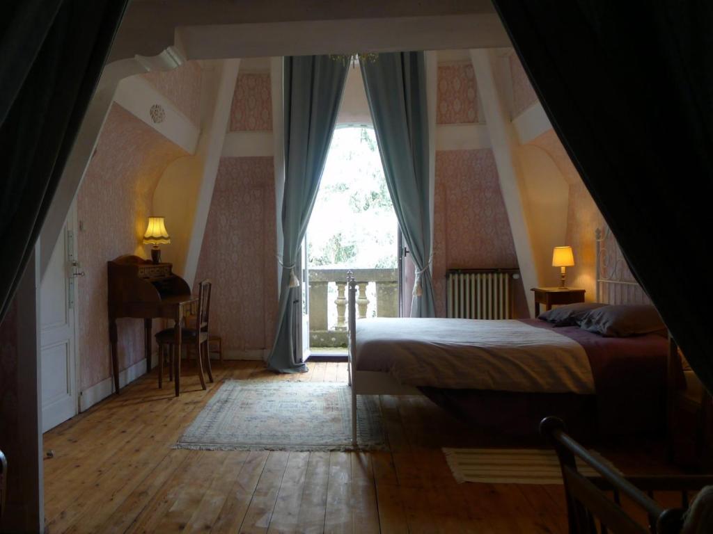 a bedroom with a bed and a large window at Le Manoir in Tarare