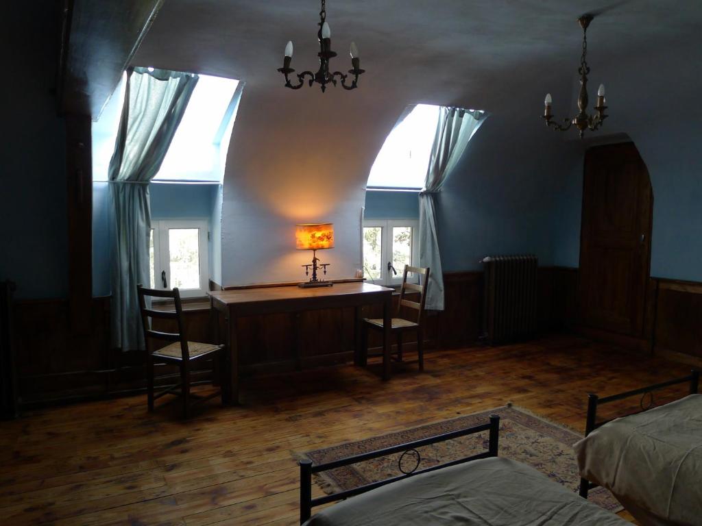 a bedroom with a desk and two chairs and a lamp at Le Manoir in Tarare