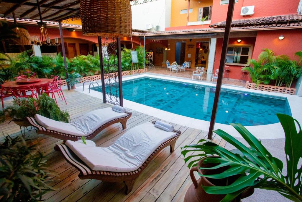 a swimming pool with chairs and a table next to a building at Pousada Jeito de Minas in Governador Valadares