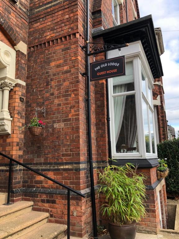 ein Schild an der Seite eines Backsteingebäudes mit Fenster in der Unterkunft The Old Lodge Guest House in Lincoln