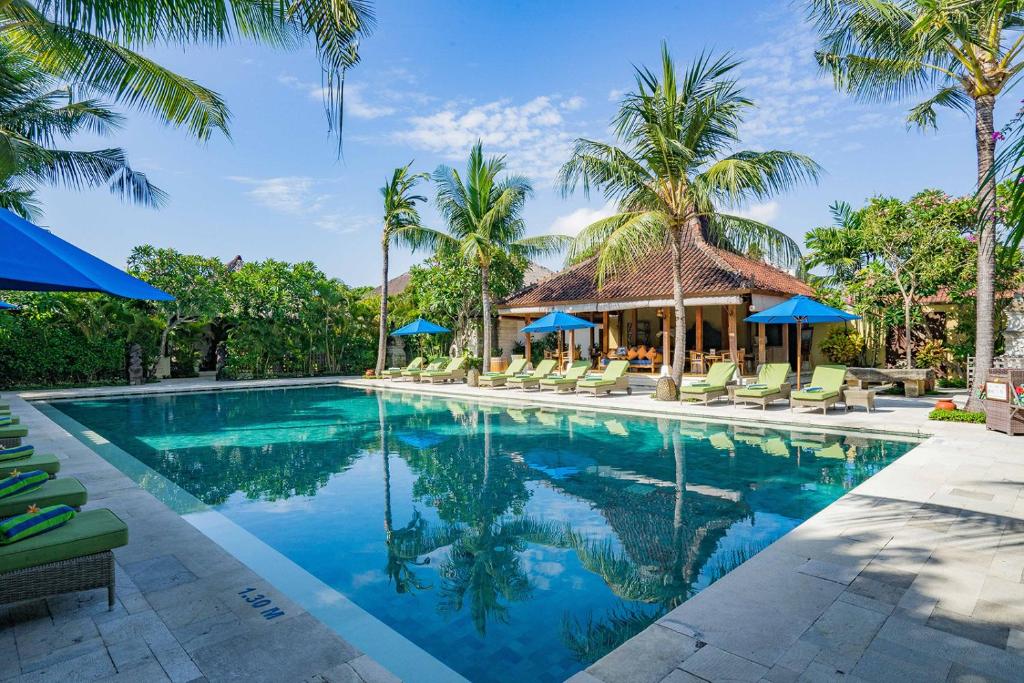 a swimming pool at a resort with palm trees at Sudamala Resort, Sanur, Bali in Sanur