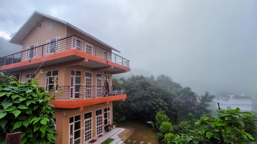 a building with a balcony on top of it at Blue Mountain Village Cottage in Nainital