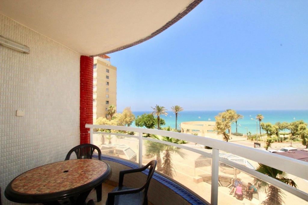 een balkon met een tafel en stoelen en de oceaan bij Royal Beach Front Apartments in Netanya