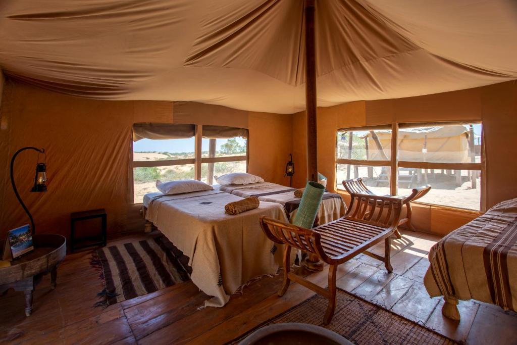 ein Schlafzimmer mit einem Bett und einem Zelt in der Unterkunft Horizons Lodges Lompoul in Lompoul