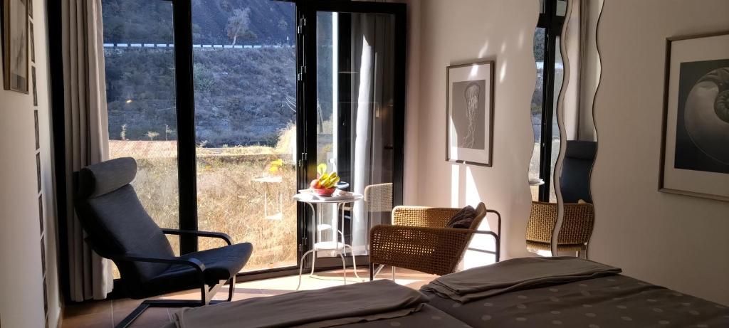 a bedroom with a bed and chairs and a large window at Casa de Isora Private apartments in Garachico